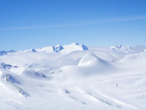 Winter landscape with snow covered slopes and blue sky, view from the top of Kitzsteinhorn mountain on . Kaprun ski resort, National Park Hohe Tauern, Austrian Alps, Europe