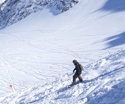 KAPRUN, AUSTRIA, March 12, 2019: Free ride piste with freerider snowboarder skiing downhill on snow covered slopes from the top of Kitzsteinhorn mountain at Kaprun ski resort. Sunny winter day