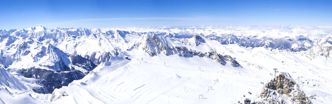 Panoramic landscape Winter view from the top of Kitzsteinhorn mountain on snow covered slopes, blue sky. Kaprun ski resort, National Park Hohe Tauern, Austrian Alps, Europe