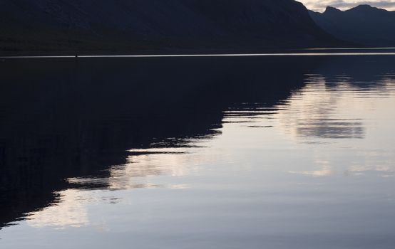 Beautiful beautiful blue orange sunset over the lake Lulealven in Saltoluokta in Sweden Lapland. Reflection of mountains, clouds and sky in clear the water. Minimalist, copy space.