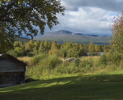 Traditional wooden cabin with view on beautiful landscape of Sarek mountains and river Kamajokk in Kvikkjokk in Swedish Lapland.