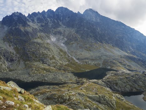 view on three mountain lake Prostredne, Velke and nizne Spisske pleso at the end of the hiking route to the Teryho Chata mountain shelter in the High Tatras in Slovakia, fog nad blue cloudy sky.