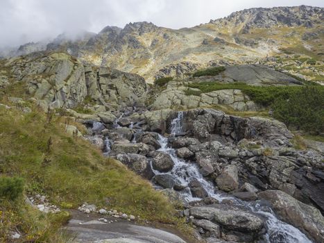 Mountain river stream cascade on footpath from Valley Mlynska Dolina Strbske pleso village and High Tatra Mountains, Slovakia, summer day