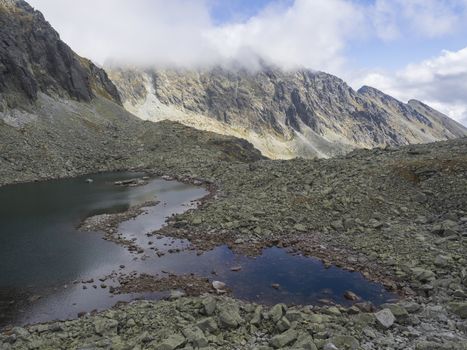 Panorama from Bystra lavka 2300m with the mountain lake Capie and in Mlynicka dolina and peak Strbsky stit 2381m , slovakian high Tatra mountains. fog and dramatic light.