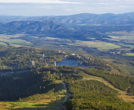 Aerial view on Strbske pleso village and blue mountain lake from chata pod soliskom with forest, hills aHigh Tatra mountains, Slovakia, summer golden hour.