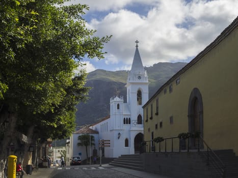 Spain, Canary islands,Tenerife, Los Silos, December 19, 2017: white church and historic buildings in old village with green trees and hills in background
