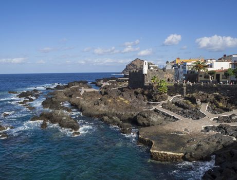View on Garachico panorama with sea pools and lava rocks village center  in Tenerife canary island spain with blue sky white clouds background