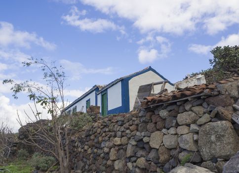 old abandoned farm, traditional rural house with stine wall in tenerife ananga mountain with blue sky background