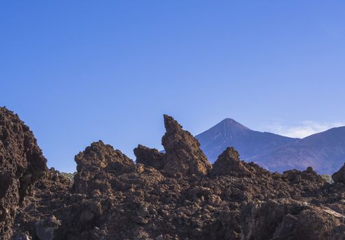 view on top of colorful volcano pico del teide highest spanish mountain from lava rock formation Roques de Garcia with clear blue sky 