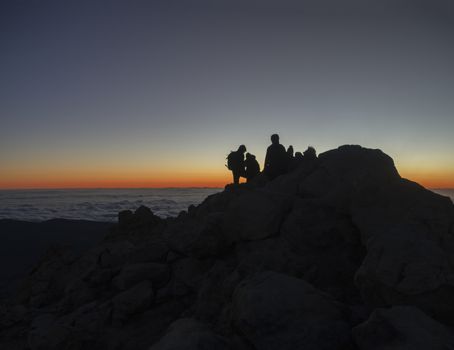 red glow before sunrise on the top of pico del teide  vulcano highest spanish mountain with silhoutte of hikers waiting on sunrise on tenerife canary island