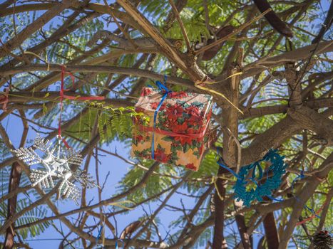 Summer Christmas trees. Tropical palm trees decorated with colourful ornaments and decorations for the holidays. Pink baubles and gift box, Tenerife, Canary Island, Spain