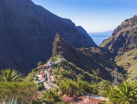 Canary Island, Tenerife  view on pitoresque Masca village with old stone houses, palm tees, beatiful green sharp hills, cliff, sea horizon and blue sky background