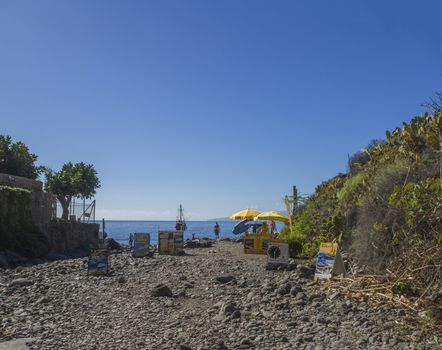 Spain, Canary islands, Tenerife, Masca, December 25, 2017: end of macsa valley with stands selling boat trip ticket with view on sea horizon and beach Playa De Masca, blue sky background