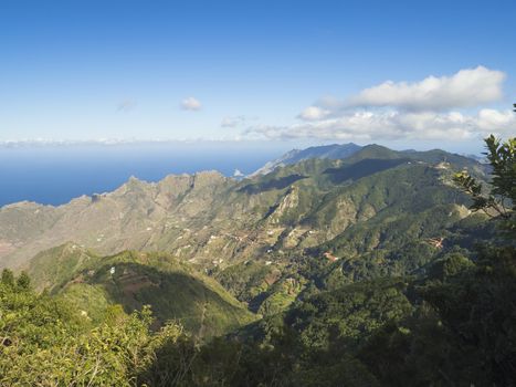 view point Amogoje, green hills with rock in the sea El Draguillo in anaga mountain, tenerife  canary island spain with dramatic blue sky white clouds background