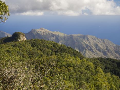 view point Amogoje with pitoresque green hills and bush, sharp rock peaks and sea in anaga mountain, tenerife  canary island spain with dramatic blue sky white clouds background