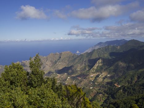 view point Amogoje, green hills with rock in the sea El Draguillo in anaga mountain, tenerife  canary island spain with dramatic blue sky white clouds background