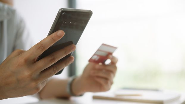 Shopping online with smartphone and credit card on hand.