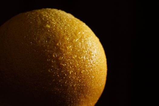 Orange fruit with drops with black background.