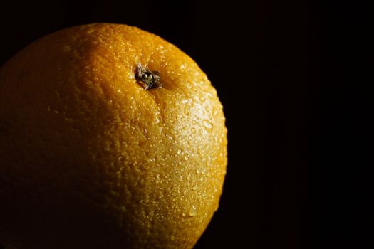 Orange fruit with drops with black background.