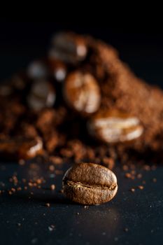 Ground coffee and coffee beans on black background.