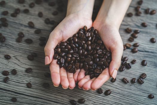 Woman's hands holding roasted coffee beans of heart shaped, closeup