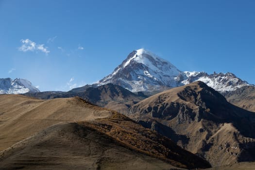 Kazbegi region of Georgia, snow capped mountains and rugged terrain. Mount Kazbegi is a dormant stratovolcano and one of the major mountains of the Caucasus located on the border of Georgia's Kazbegi District and Russian Republic of North Ossetia Alania. High quality photo