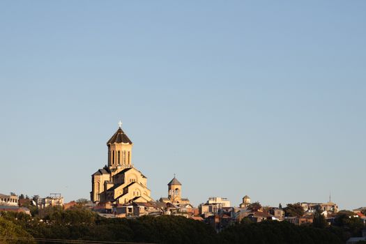 Holy Trinity Cathedral of Tbilisi. Cathedral of Orthodox Christianity against blue sky with the city at the base, Beautiful late afternoon light shot from Narikala Fortress