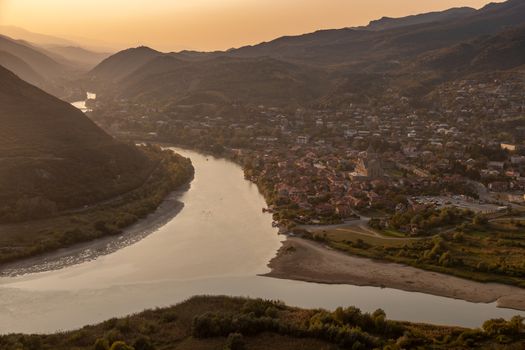 Mtskheta, Georgia, seen from Jvari Monastery showing river confluence and mountains in the background with low sun, very beautiful, golden yellow