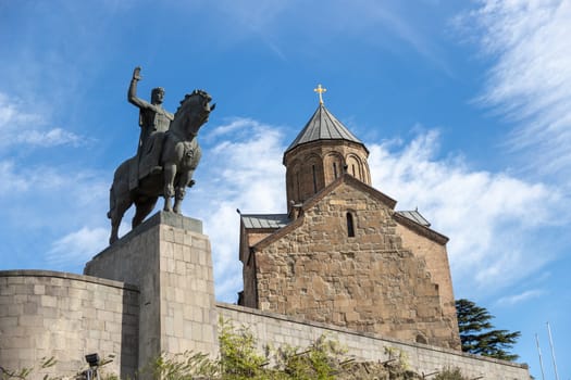 Metekhi church and the statue of King Vakhtang Gorgasali in the old town of Tbilisi, the capital of Georgia. View up to statue against blue sky with cloudsHigh quality photo