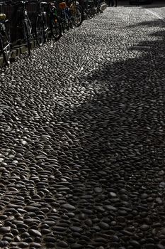 Cobbles in Oxford, Radcliffe Square. Street paved with cobbles in low sun light giving great texture. Bicycles leaning against fence. High quality photo