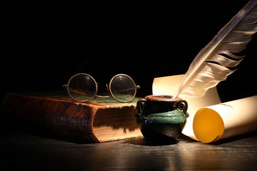 Vintage still life with old book and quill pen on dark background