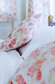 Bright bedroom interior with flower pattern pillows on bed