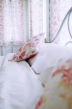 Bright bedroom interior with flower pattern pillows on bed