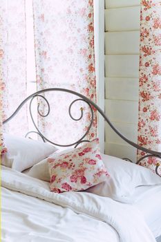 Bright bedroom interior with flower pattern pillows on bed
