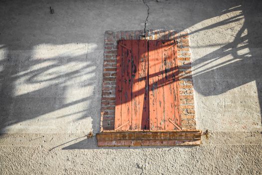 An old window decorated by the play of light and shadow.