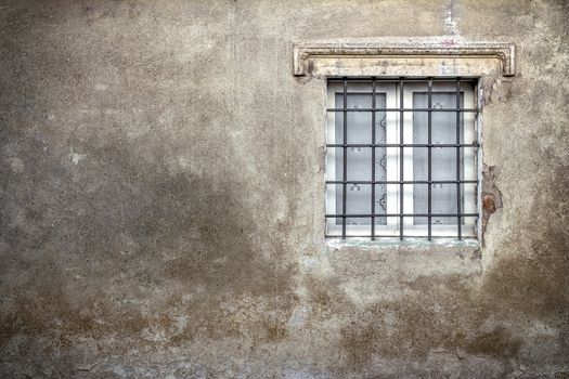 An old facade with peeling plaster and old window.