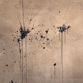 Splashes of black paint on an old wall.