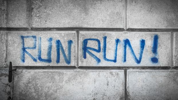 Blue Hand Written "RUN RUN" Graffiti on old stone wall. Ideal for concepts and backgrounds.