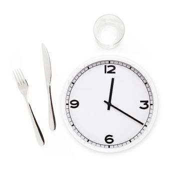 Fork, knife, glass, and white round clock isolated in white background. Time to eat concept.