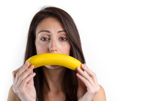 Young woman making sad gesture with banana over isolated white background