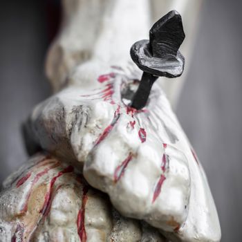 Detail of feet with blood of a wooden crucifix. Defocused blurry background.