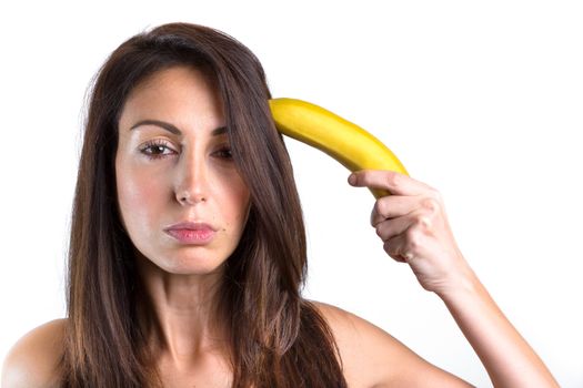 Conceptual portrait of a young woman trying to shoot herself with a banana gun. Space for text.