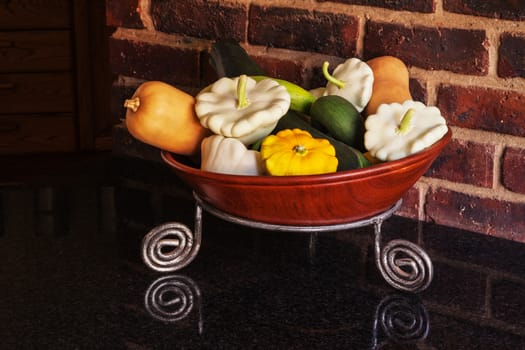 An arrangement of different pumpkins in a wooden bowl showing the gardener's successful crop.