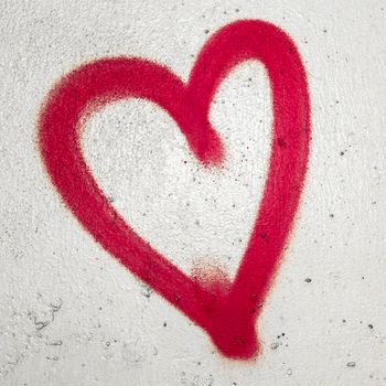 Concept or conceptual painted red abstract heart shape love symbol, dirty wall background, metaphor to urban and romantic valentine, grungy style.