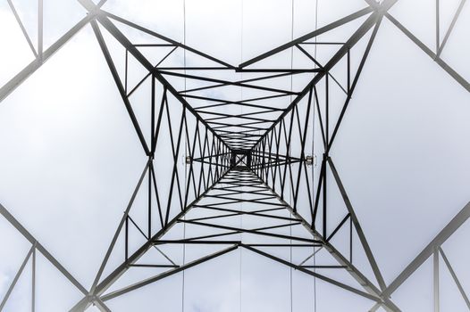 High voltage pylon into the fog. Bottom view. Pattern of metal architecture.