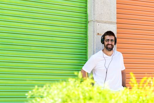 Cool trendy funny beard guy in headphones listening music on colored background.