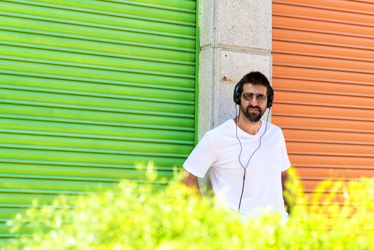 Cool trendy funny beard guy in headphones listening music on colored background.