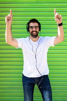 Cool trendy funny beard guy in headphones listening music on colored background.