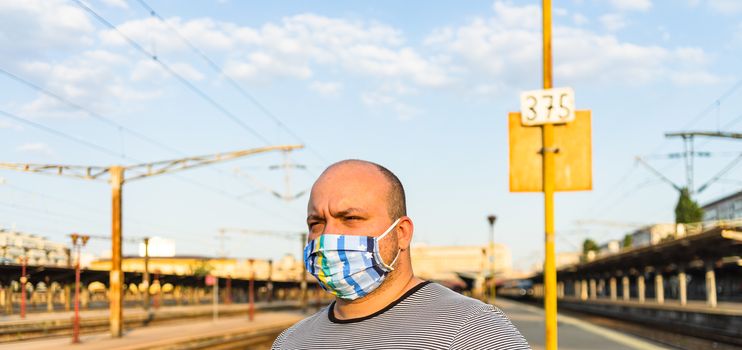 Young man with medical protective face mask illustrates pandemic coronavirus disease on blurred background. SARS-CoV-2 outbreak in Europe. Changes and complications caused by epidemic