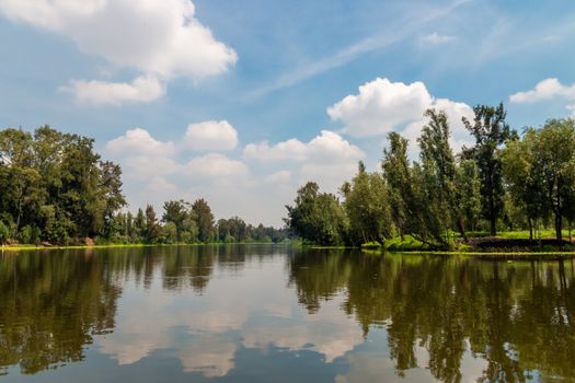 Landscape of the Cuemanco canal in Xochimilco, Mexico City. Calm river. Trajineras. Xochimilco. CDMX. The river flows in spring through the woods